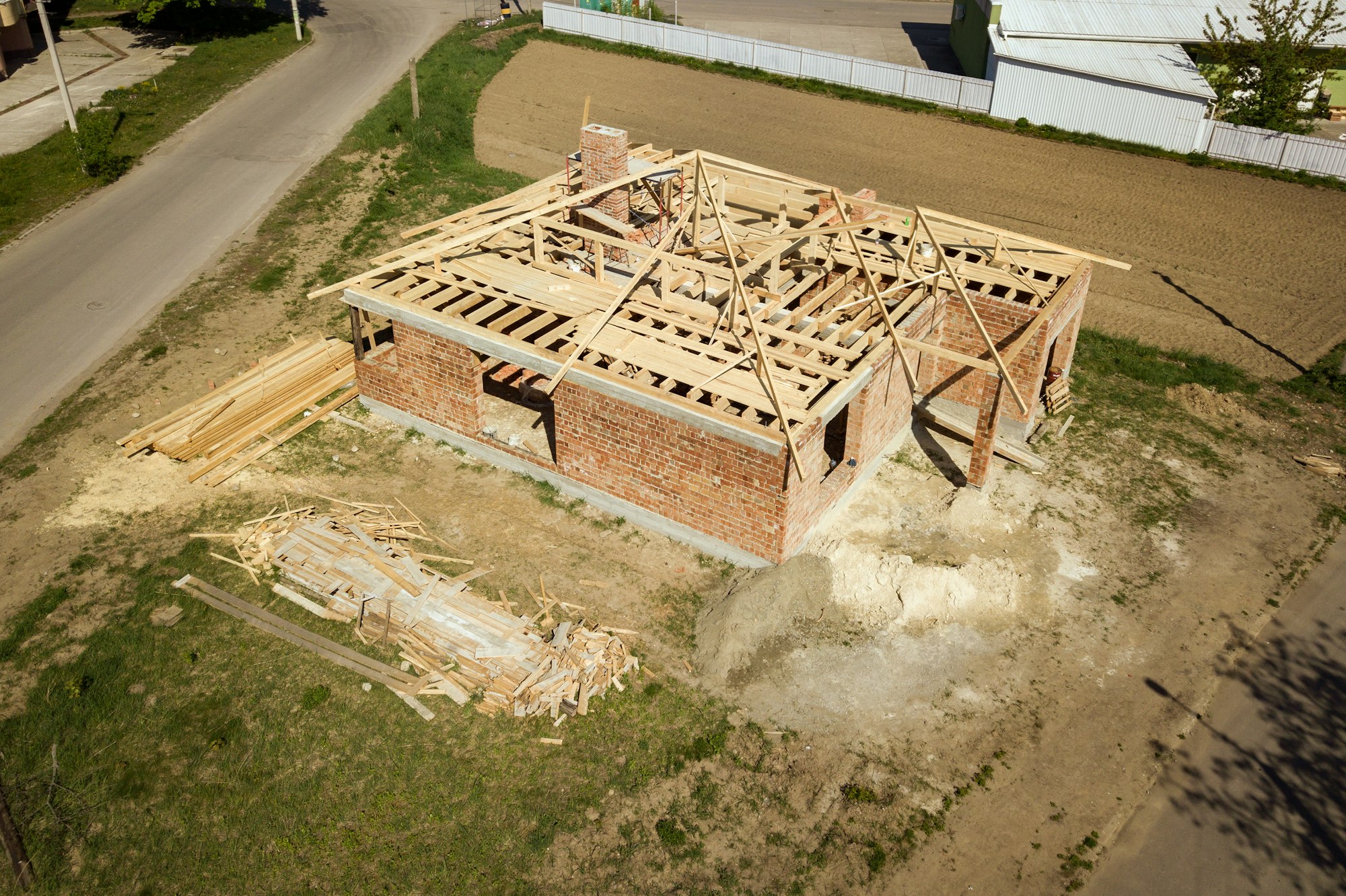 Aerial view of unfinished brick house with wooden roof frame structure under construction