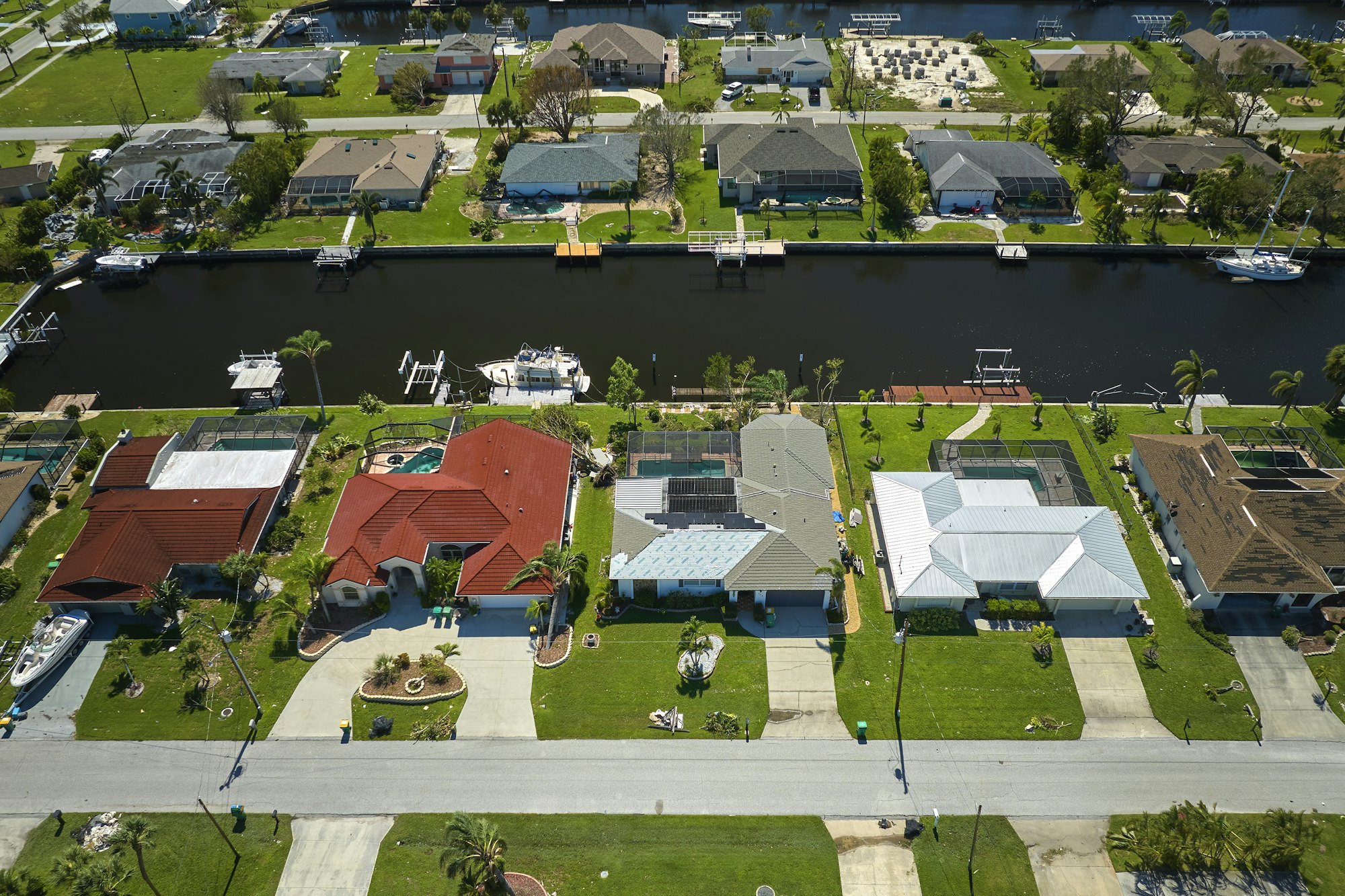 Damaged home rooftops after hurricane Ian in Florida coastal residential area.